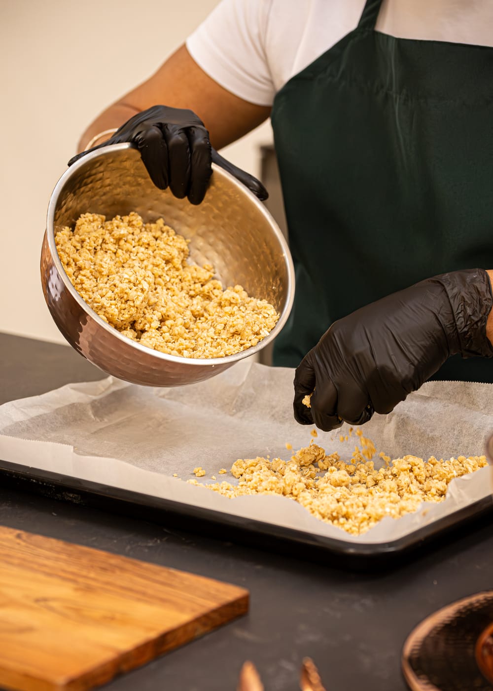 Flapjack mix being poured from a copper bowl onto a lined baking tray